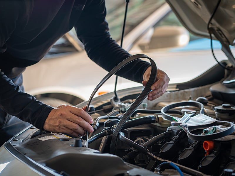 Technician inspecting and replacing an engine belt
